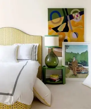 neutral bedroom with yellow upholstered bed and layered artwork