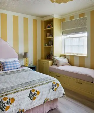 yellow striped wallpaper in childrens bedroom with bench nook and pink bed