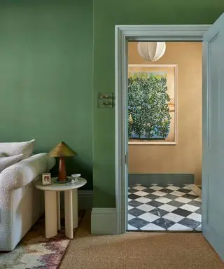 living room with green walls, jute carpet and light blue doorframe