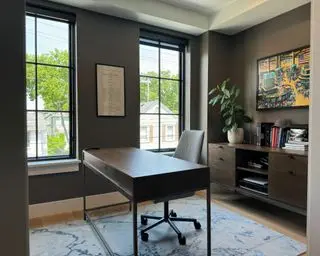 home office with dark gray walls, wooden furniture and yellow artwork