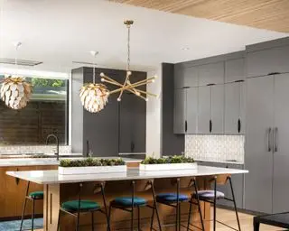 modern kitchen with dark gray cabinets, white kitchen island, gold pendant lights