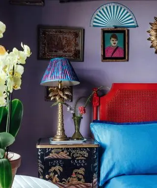 maximal bedroom with purple wall, artwork on walls and red headboard