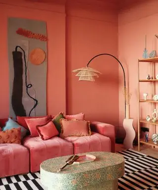 living room with brick red walls, pink sofa and large artwork on walls