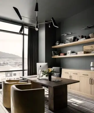 An office with dark gray walls and wooden floating shelves