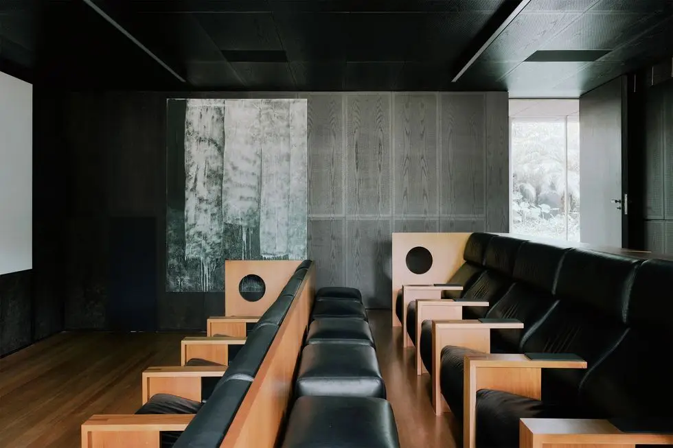 a media room with a row of seats in black velvet with wood circular cutouts on the side