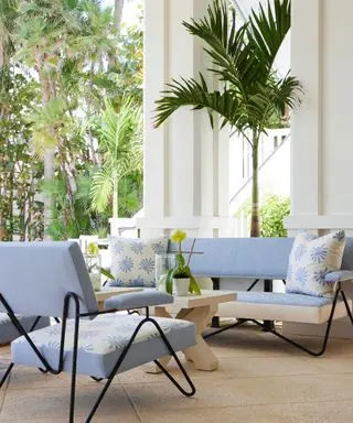 outdoor seating area with light blue chairs, floral cushions and green trees in background