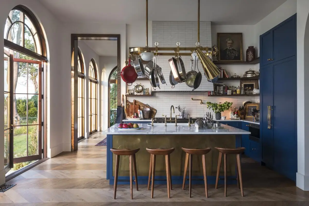 A 1920s-style kitchen has blue cabinets and up-to-date appliances by Wolf and Sub-Zero and brass fittings from Waterworks.