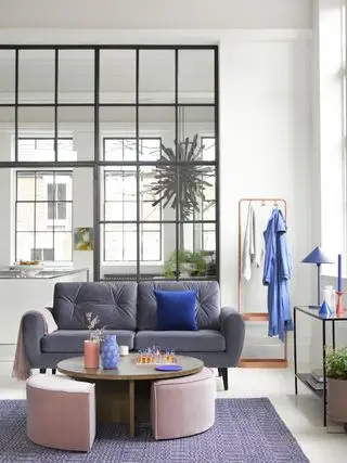 open plan living room with critall windows dividing the space, purple rug and pink pouffes