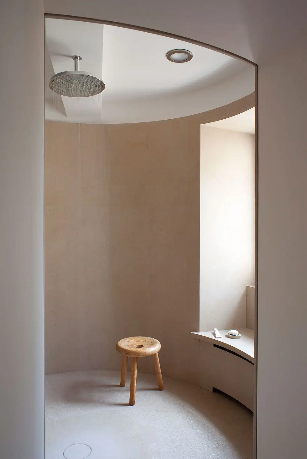 open rounded shower room with a three legged wood stool and window seat