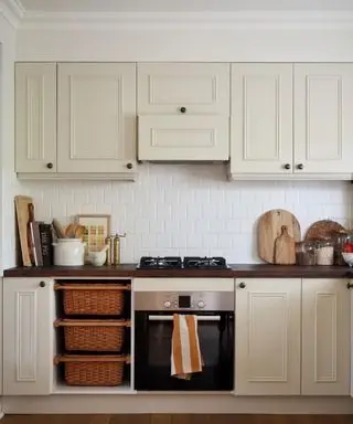 Taupe kitchen cabinets paired with aged brass hardware and a dark wood countertop