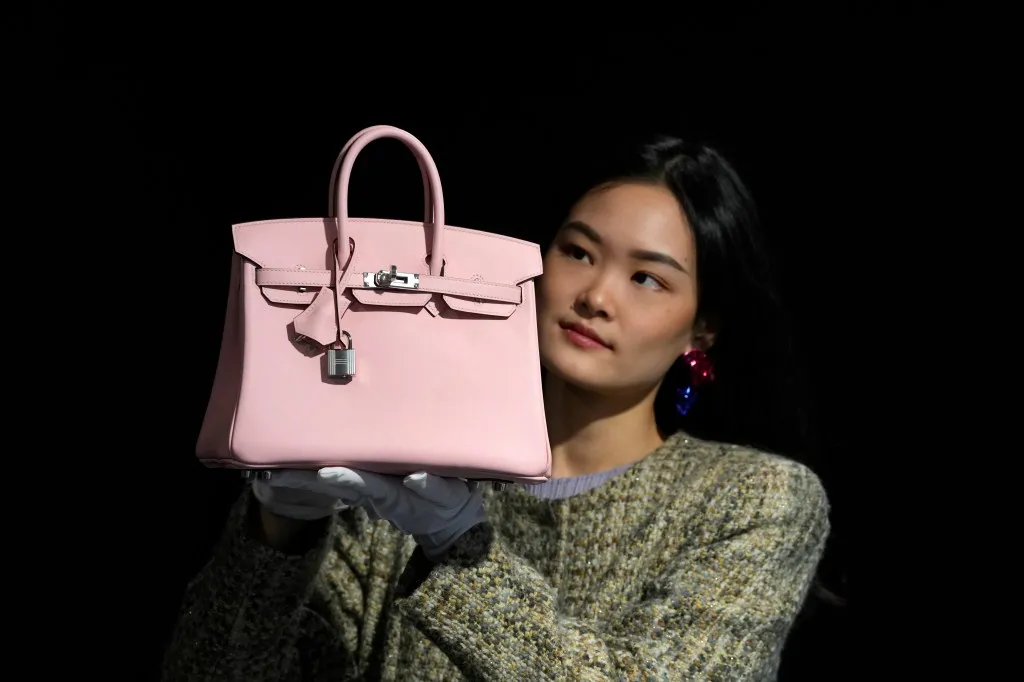 Hermes: Rose Sakura Swift Leather Birkin 25 handbag, estimated at 18,000-22,000 UK Pounds at the Bonhams auction in London, displayed by an employee.