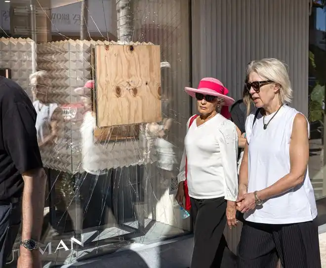 Women walk past the David Yurman jewelry store along Worth Avenue in Palm Beach where a board covers a cracked window following a recent smash-and-grab burglary February 20, 2024.