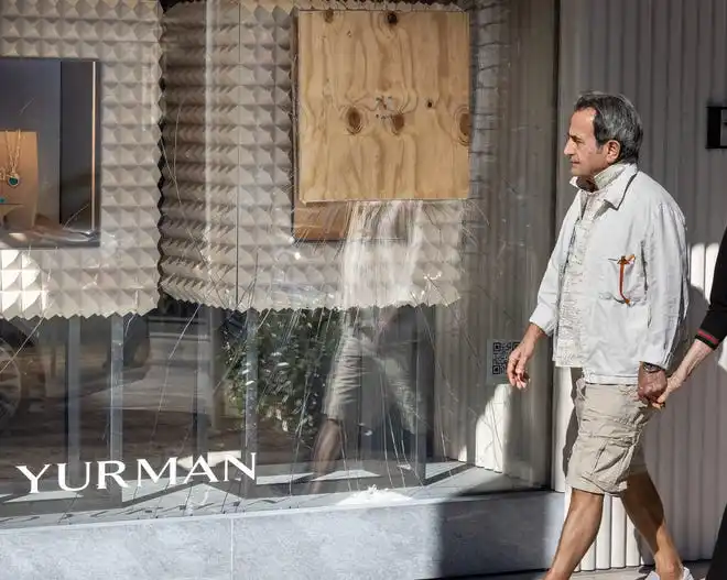 A man walks past the David Yurman jewelry store along Worth Avenue in Palm Beach where a board covers a cracked window following a recent smash-and-grab burglary February 20, 2024.