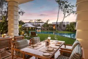 BIJAL club house with dining table looking across grounds to pool