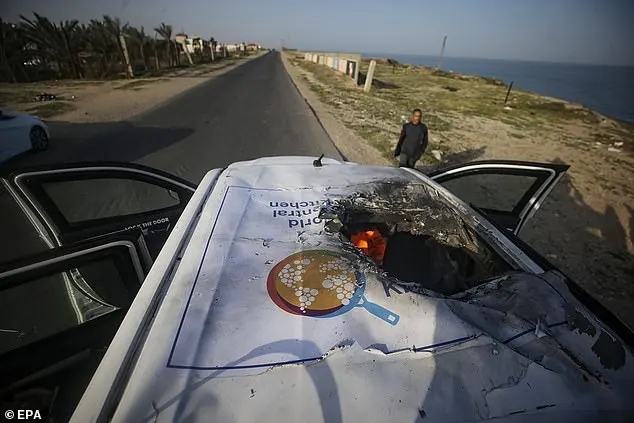 A man stands by a destroyed car of the NGO World Central Kitchen as it sits on Al Rashid road