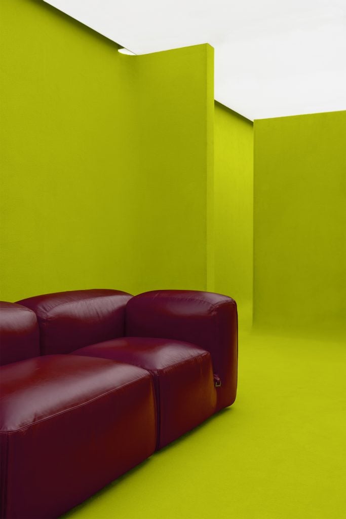 an oxblood modern Italian designer couch is in an acid green maze