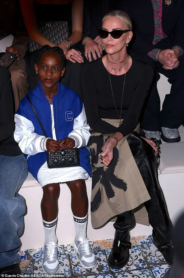 At her side, her youngest daughter looked cool in a white, quilted dress teamed with an oversize, royal blue varsity jacket. August also donned white and gray sneakers with tall socks