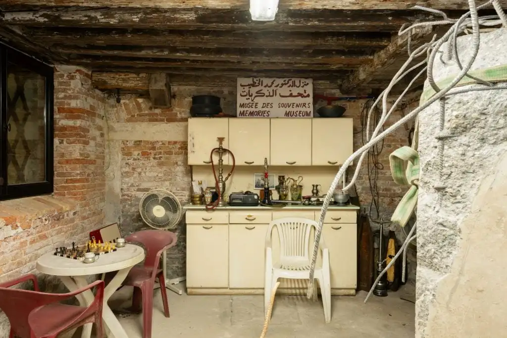 a wooden basement room that is dusty and has sand bags and old plastic chairs and fans and hookah pipes