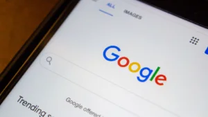 Closeup logo of Google.com website on an iPhone on wooden table. GOOG stock and Google layoffs