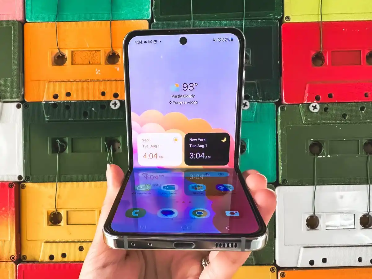 Samsung's Galaxy Z Flip 5 pictured half-open against a wall of colorful cassette tapes.