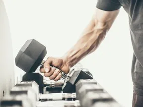 Unrecognizable man taking dumbbells in a gym.