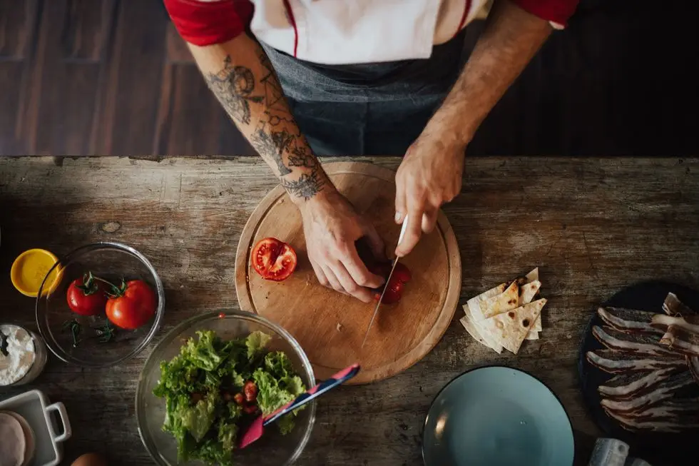 chef uses the knife to slice tomato into smaller pieces for salad