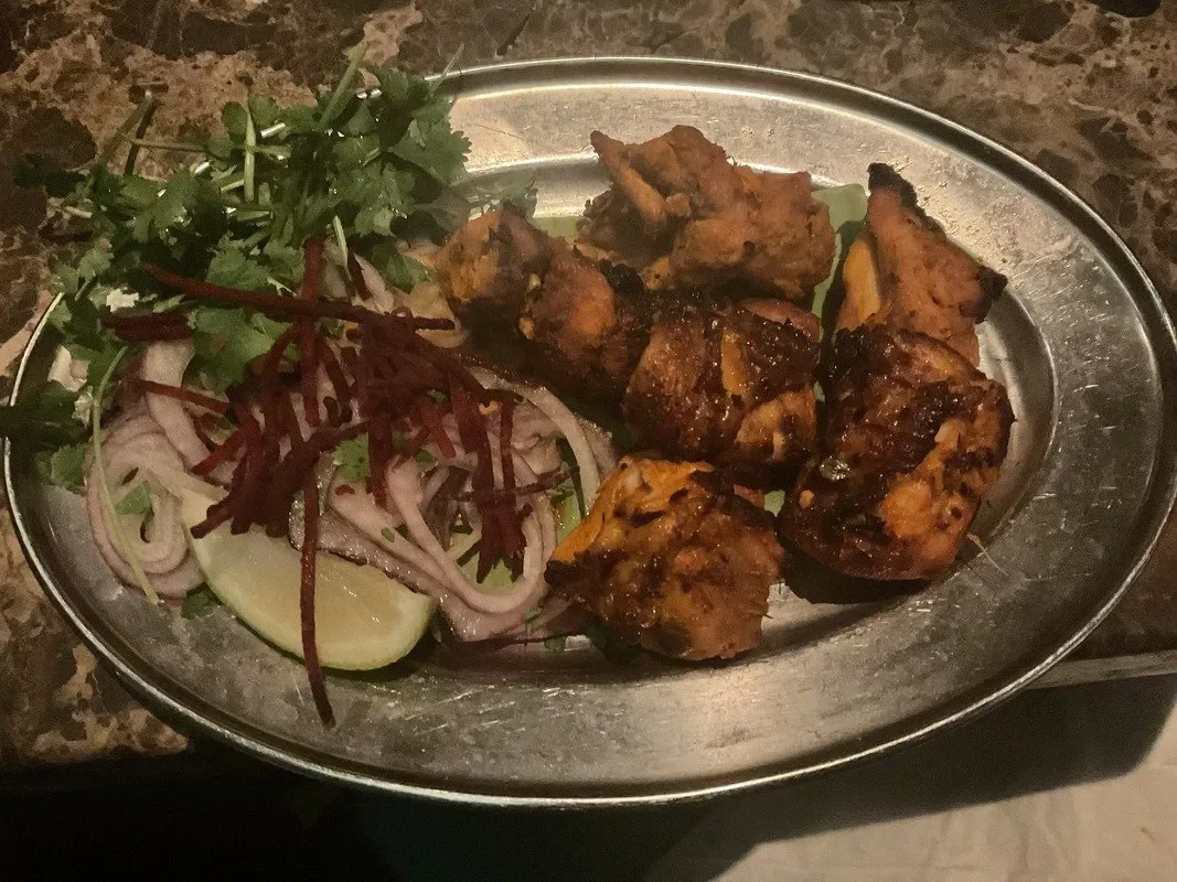 pieces of marinated and cooked chicken on a dish with a bit of salad