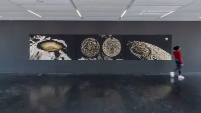 Installation view of a triptych tapestry showing images of the moon.