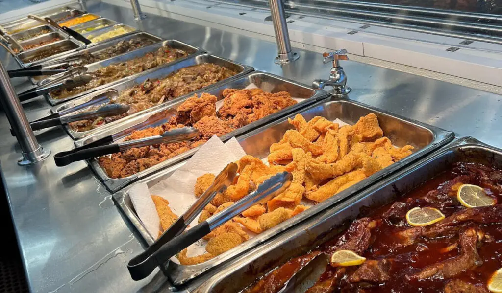 Trays of buffet-style meats in sauces under warming lamps