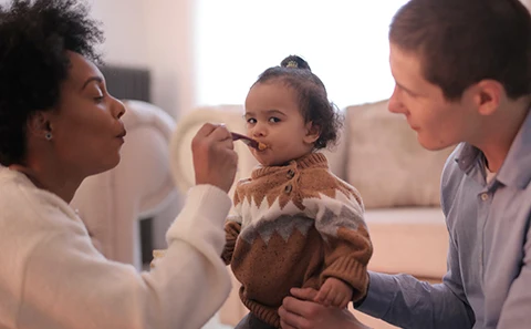 Toddler being fed by parents