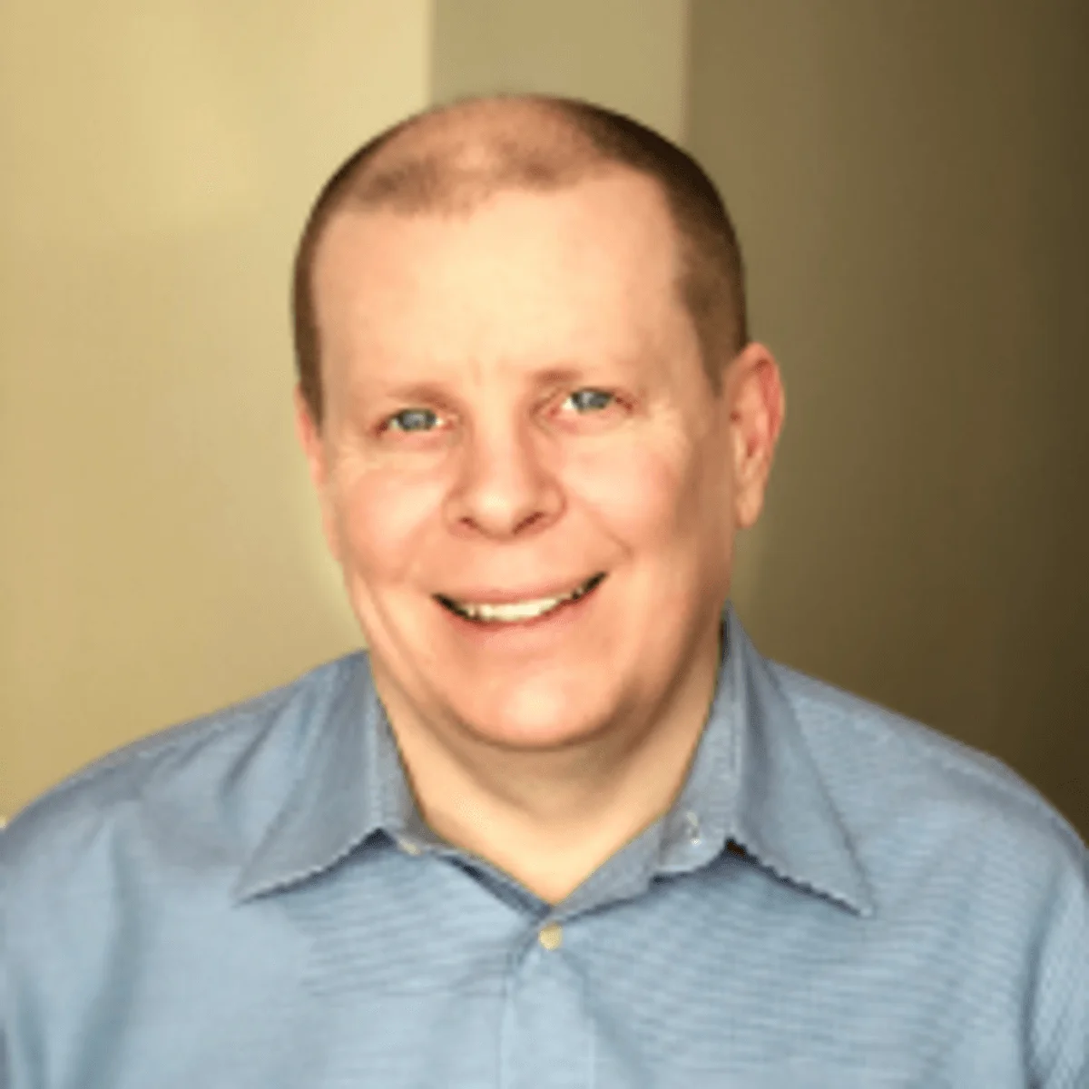 John Topinka smiles, wearing a blue shirt.