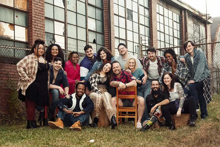 Bradley Moore sits in a large crowd of fellow theatre performers, cast and crew