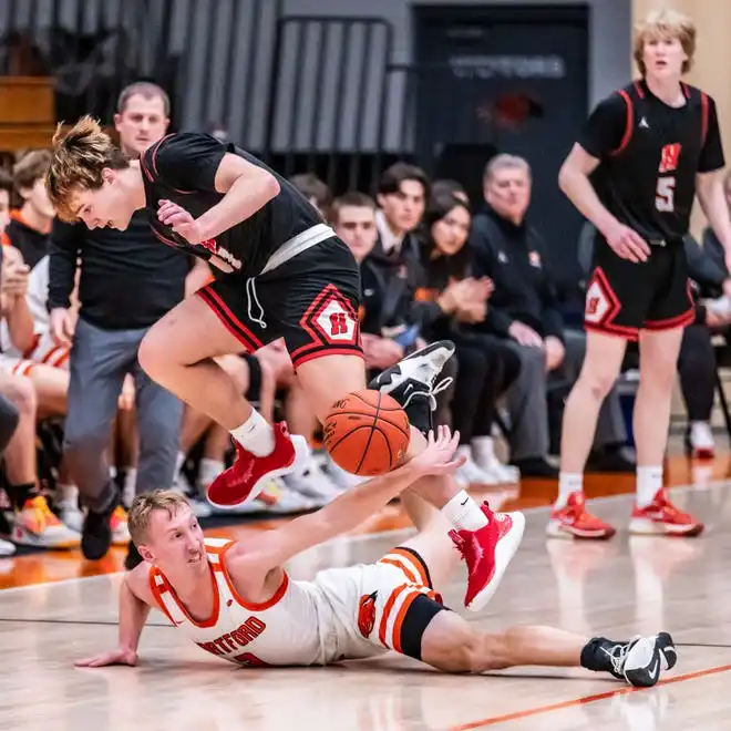 Homestead's Tommy O'Hagan (1) hurdles Hartford's RJ Thomae (3) as they battle for a loose ball at Hartford, Tuesday, Jan. 30, 2024.