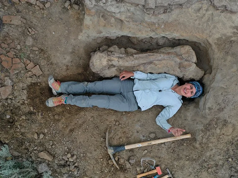 Lying next to a dinosaur long bone at Dinosaur Provincial Park, Alberta.