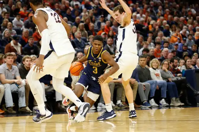 Jan 31, 2024; Charlottesville, Virginia, USA; Notre Dame Fighting Irish guard Markus Burton (3) dribbles the ball as Virginia Cavaliers forward Jacob Groves (34) and Cavaliers forward Jordan Minor (22) defend during the first half at John Paul Jones Arena. Mandatory Credit: Amber Searls-USA TODAY Sports