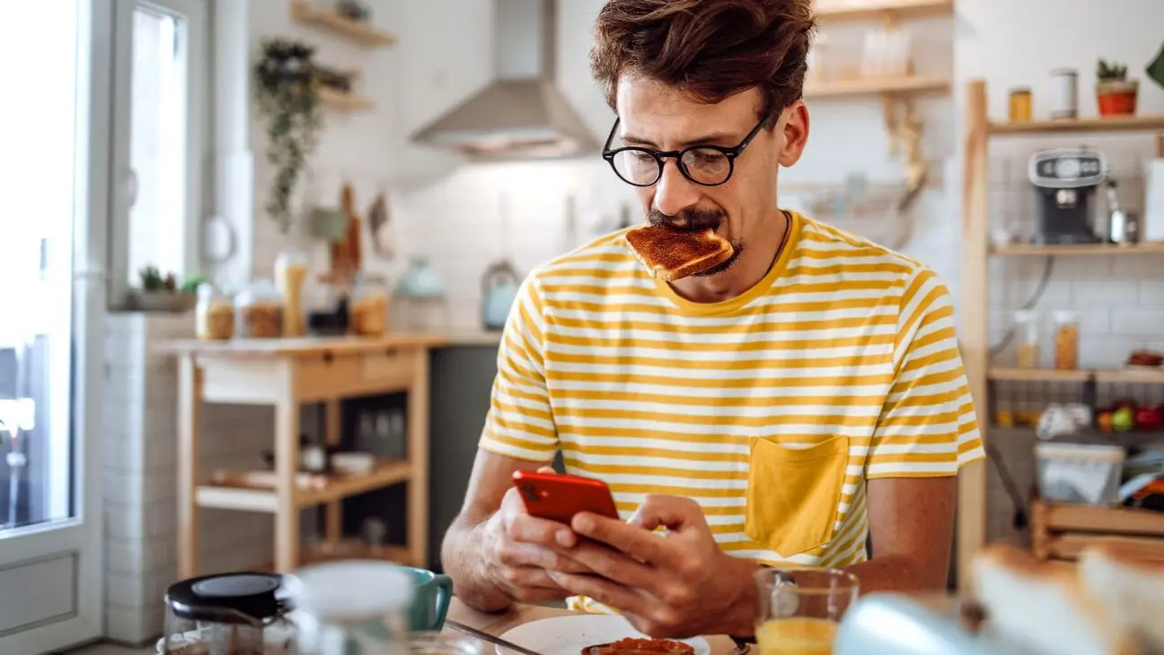 Male eating toast while scrolling on phone