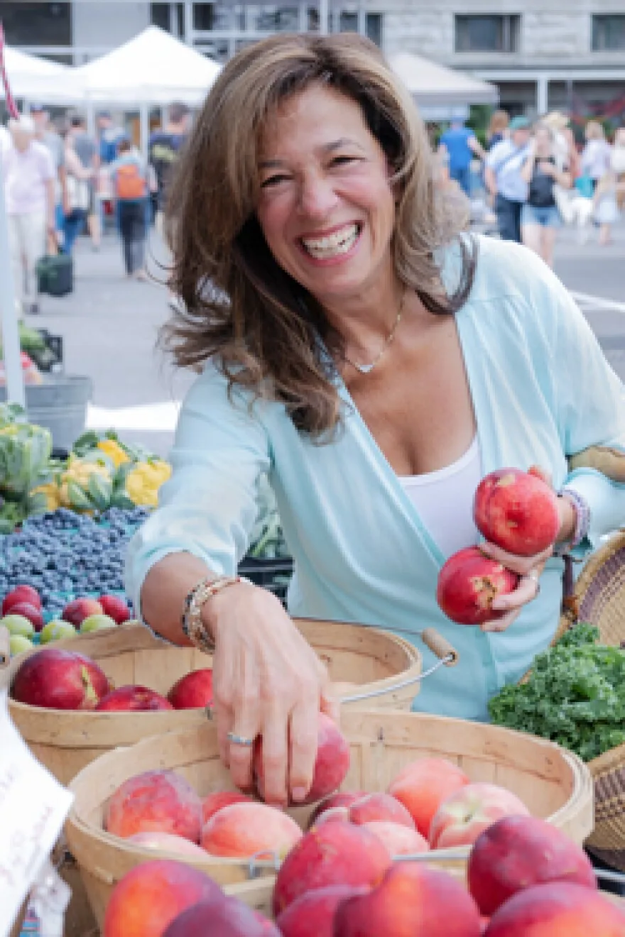 Holly Shelowitz holding apples at a farmers' market