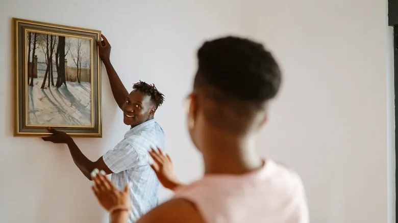 two people hanging a painting