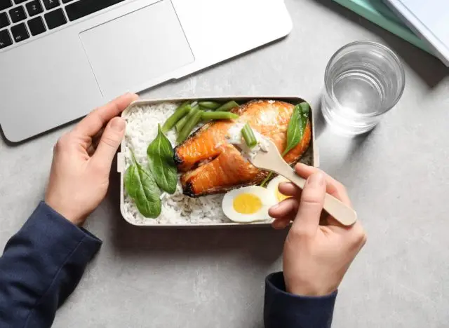 woman eating fish, rice, veggies, and eggs