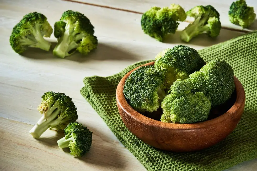 fresh raw broccoli in bowl on rustic table