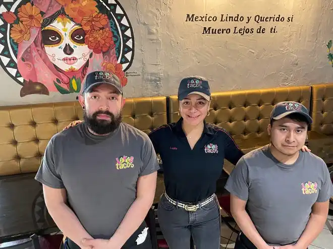 Lupita Chavez (center), co-owner of Lokos Tacos, stands with employees Daniel Castillo (left) and Isaac Ihetua in front of a wall mural at the new Lokos Tacos on Boy Scout Road in Augusta. The art replicates mural work at the smaller, original Lokos on Washington Road.