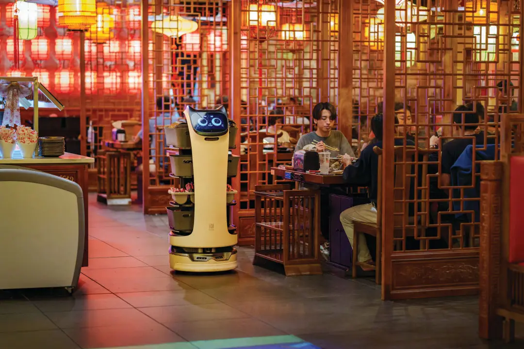 A robot assists servers in bussing tables.