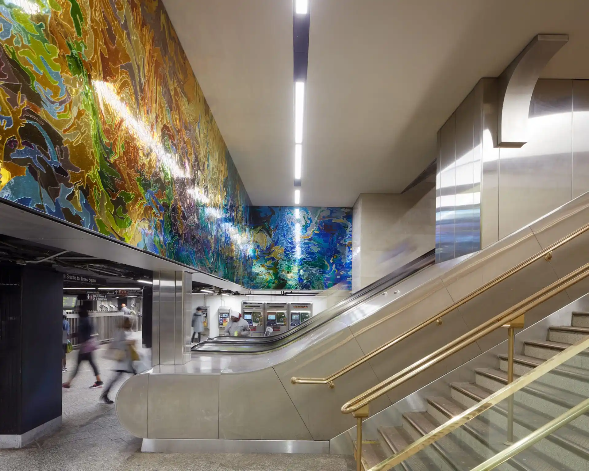A large glass mural above the escalators of a subway station in New York.