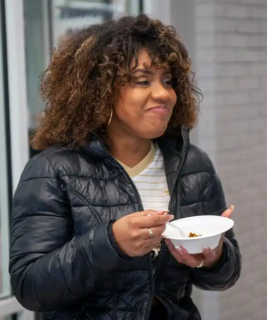 Dircelene Ramos enjoys a sweet potato black bean burger served up by MetroWest YMCA Director of Nutrition Maggie Lynch, Feb. 8, 2024, for National Heart Health Month.