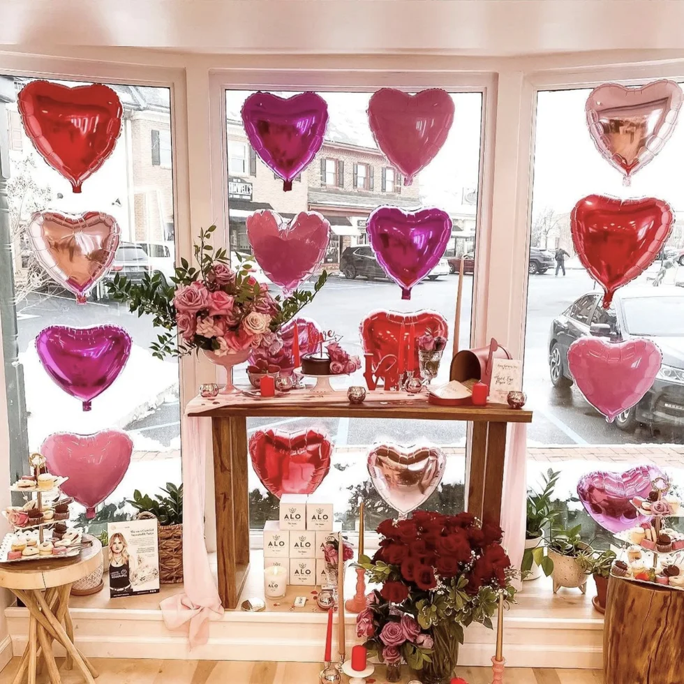 a room with a shelf with red and white vases and flowers