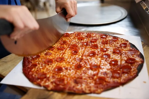 May Lee cuts a tavern-style pepperoni pizza at Bungalow by...