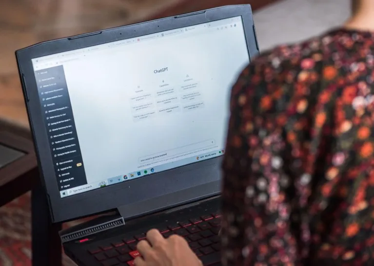 A woman working on a laptop with the ChatGPT interface visible on the screen