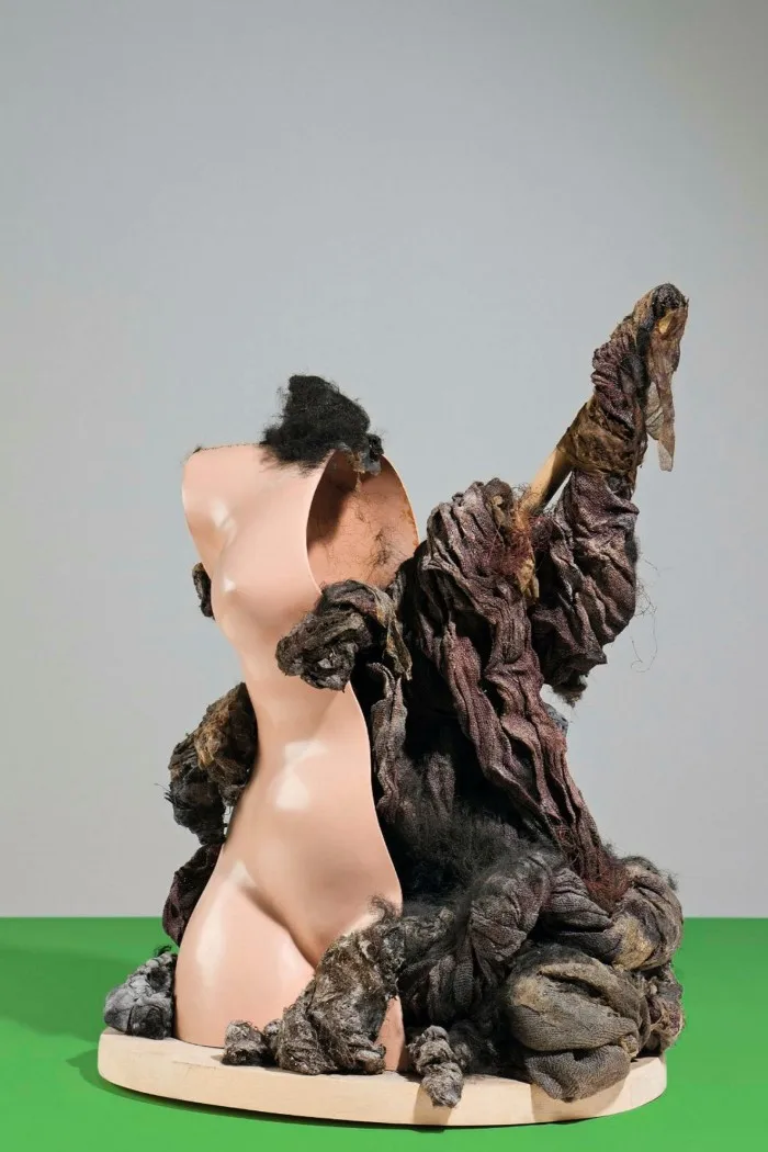 A human-like torso sculpture sliced down the middle with dirty rags pouring out