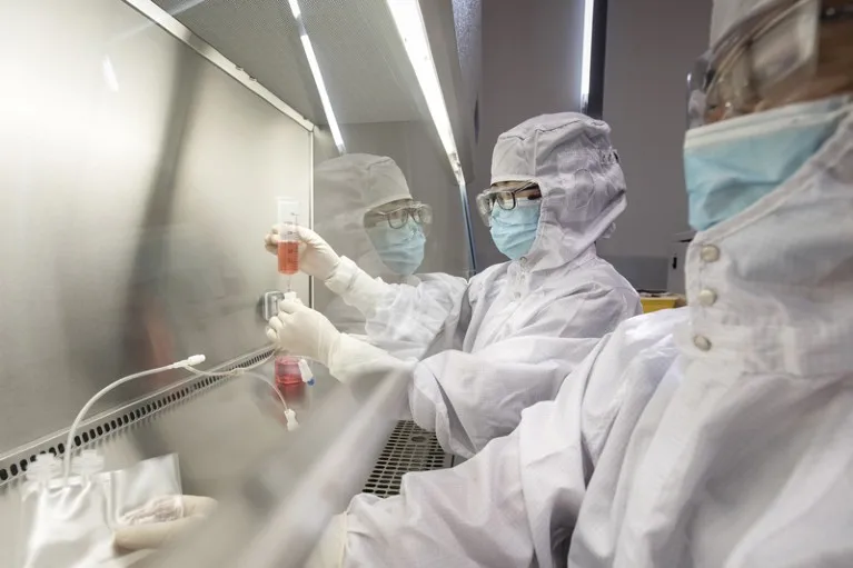 Technicians wearing full PPE work in a lab