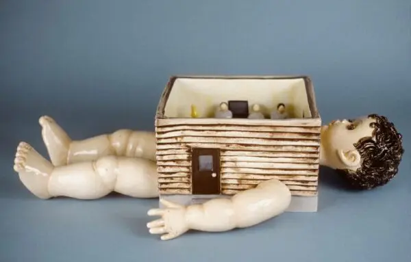 A photograph of a ceramic work featuring a child figure with a square room as its body.